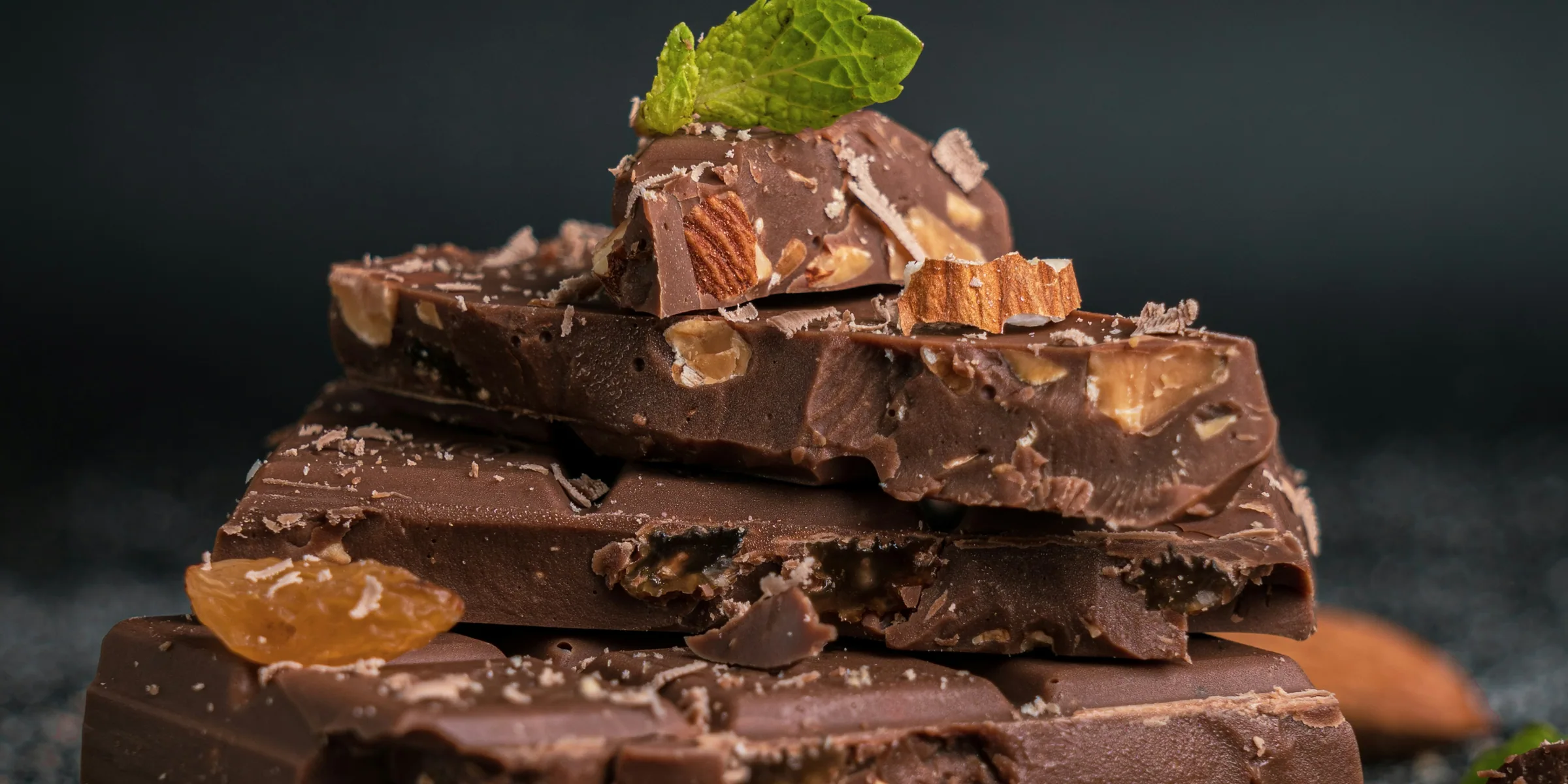 Hand pouring tempered chocolate over a row of moulded shells